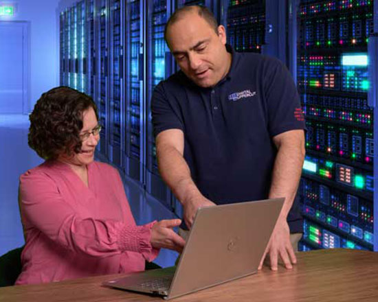 Max Avrukin working with cybersecurity client at laptop in server room.
